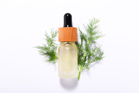 Bottle of essential oil and fresh dill on white background, top viewの写真素材