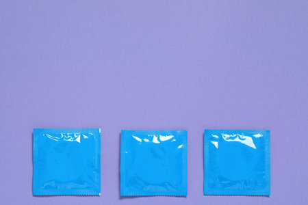 Condom packages on purple background, flat lay and space for text. Safe sexの写真素材