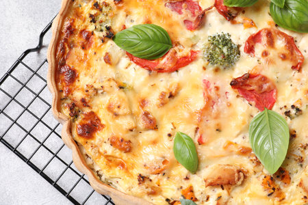 Tasty quiche with tomatoes, basil and cheese on light textured table, top viewの写真素材