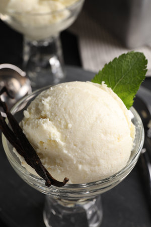 Tasty ice cream with vanilla pods in glass dessert bowl on table, closeupの写真素材