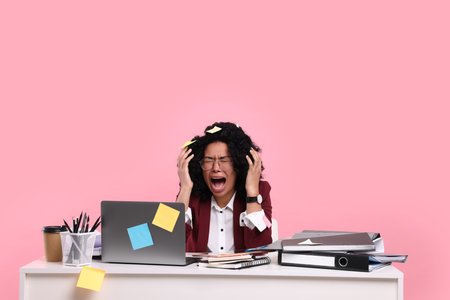 Stressful deadline. Screaming woman at white desk against pink background, space for text. Sticky notes everywhere as remindersの写真素材