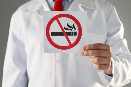 Doctor holding card with no smoking sign on gray background, closeupの写真素材