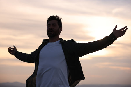 Feeling freedom. Happy man with wide open arms against sky outdoors, low angle view