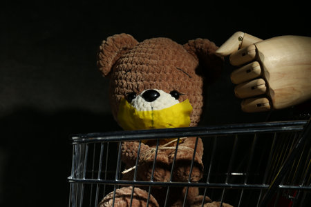 Stop child abuse. Mannequin hand and bear with taped mouth on black background, closeupの写真素材