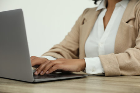 Woman using laptop at wooden desk indoors, closeupの写真素材