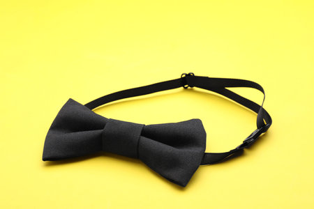 Stylish black bow tie on yellow backgroundの写真素材