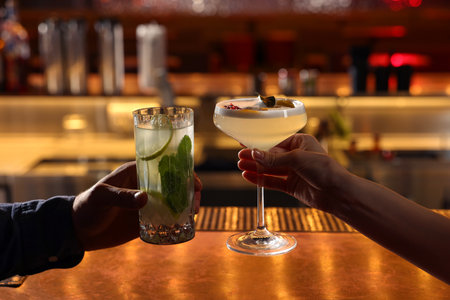People holding glasses with fresh cocktails at bar counter, closeup
