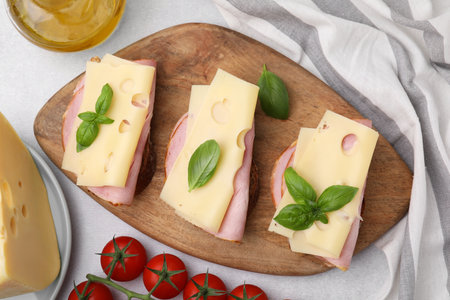 Delicious sandwiches with ham, cheese and products on light table, flat layの写真素材