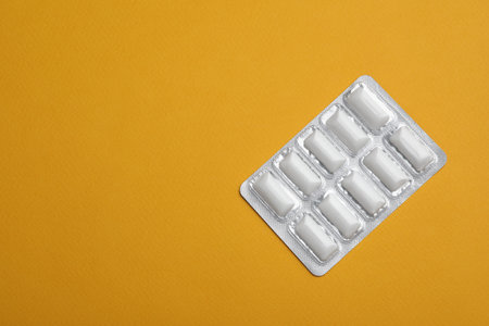 Blister of chewing gums on orange background, top view. Space for textの写真素材