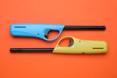 Gas lighters on orange background, flat layの写真素材