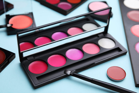 Cream lipstick palettes and brush on light turquoise background, closeup. Professional cosmetic productの写真素材