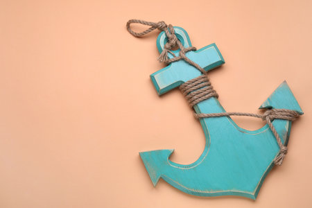 Wooden anchor figure on pale orange background, top view. Space for textの写真素材