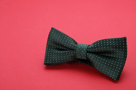 Stylish black bow tie with polka dot pattern on red background, space for textの写真素材