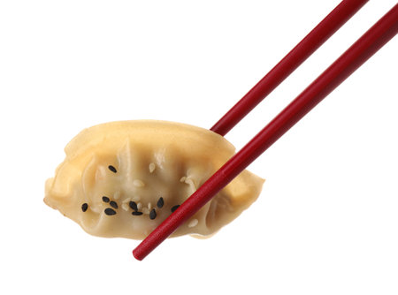 Chopsticks with delicious gyoza (asian dumpling) and sesame isolated on whiteの写真素材