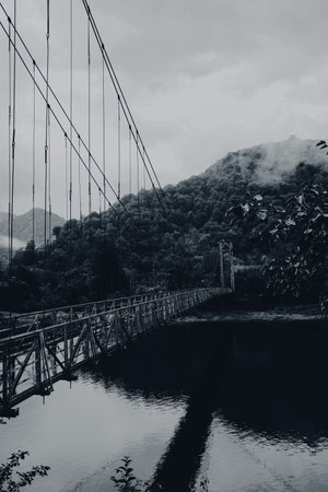Beautiful view on rusty metal bridge over river in mountains. Black and white effectの写真素材