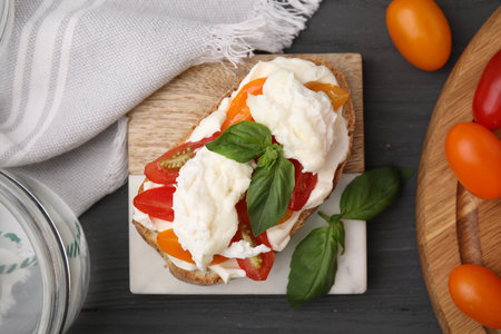 Delicious sandwich with burrata cheese and tomatoes served on gray wooden table, flat layの写真素材