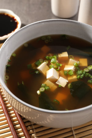 Bowl of delicious miso soup with tofu and chopsticks on bamboo mat, closeupの写真素材