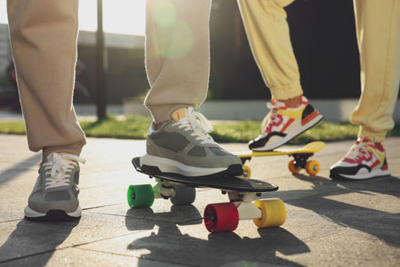 Woman and man with skateboards wearing stylish sneakers outdoors, closeupの写真素材