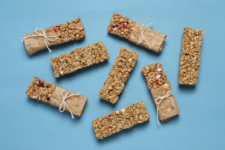 Different tasty granola bars on light blue background, flat layの写真素材