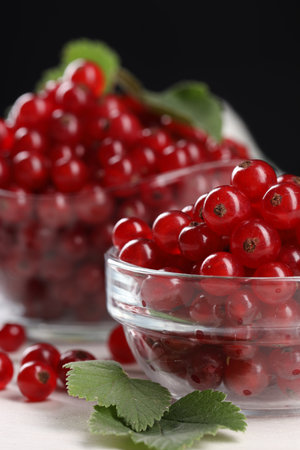 Many ripe red currents and leaves on white table, closeup