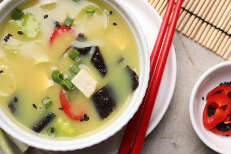 Bowl of delicious miso soup with tofu served on light gray table, flat layの写真素材