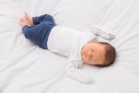Cute newborn baby sleeping on white soft bedの写真素材