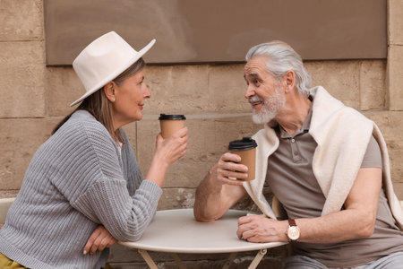 Affectionate senior couple sitting in outdoor cafe and drinking coffeeの写真素材