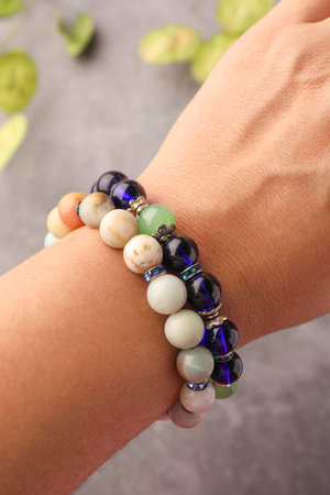 Woman wearing beautiful bracelets with gemstones on blurred background, closeupの写真素材