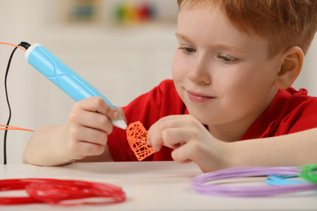 Boy drawing with stylish 3D pen at white table