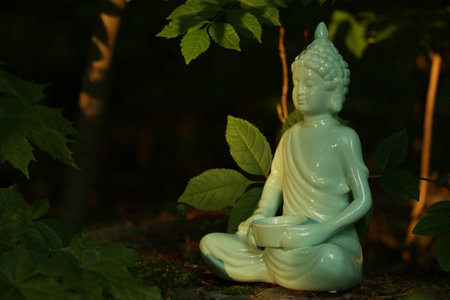 Decorative Buddha statue on stone under tree, space for textの写真素材
