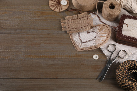 Pieces of burlap fabric with different stitches and sewing tools on wooden table, above view. Space for textの写真素材