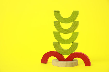 Colorful wooden pieces of playing set on yellow background, space for text. Educational toy for motor skills developmentの写真素材