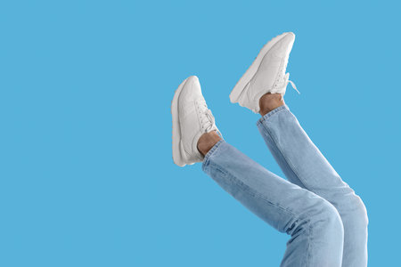 Man wearing stylish sneakers on light blue background, closeup. Space for text