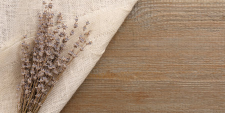 Beautiful dry lavender flowers and burlap fabric on wooden table, top view. Space for textの写真素材