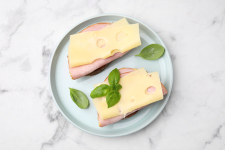 Delicious sandwiches with ham and cheese on white marble table, top viewの写真素材