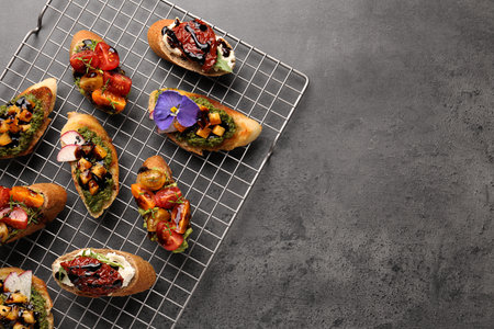 Delicious bruschettas with different toppings and balsamic vinegar on gray textured table, flat lay....