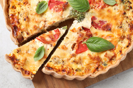 Tasty quiche with tomatoes, basil and cheese on light textured table, top viewの写真素材