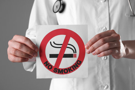 Doctor holding card with no smoking sign on gray background, closeupの写真素材