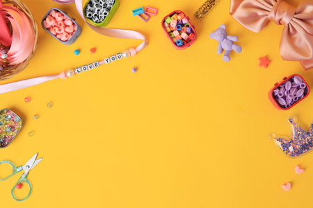 Kid`s handmade jewelry kit. Colorful beads, ribbon, bow and different supplies on orange background,...