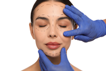Doctor checking patient's face before cosmetic surgery operation on white background, closeupの写真素材