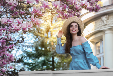 Beautiful woman near blossoming magnolia tree on spring dayの写真素材