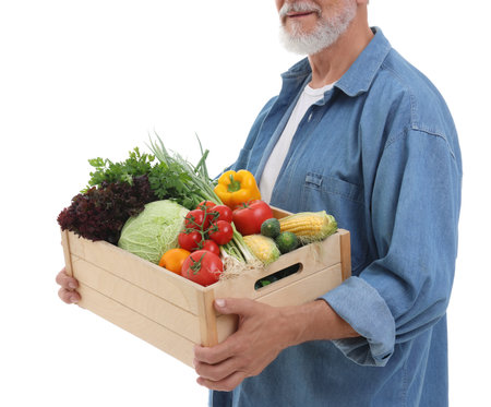 Harvesting season. Farmer holding wooden crate with vegetables on white background, closeupの写真素材