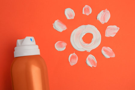 Drawing of sun and bottle with sunscreen on coral background, top view. Skin protectionの写真素材