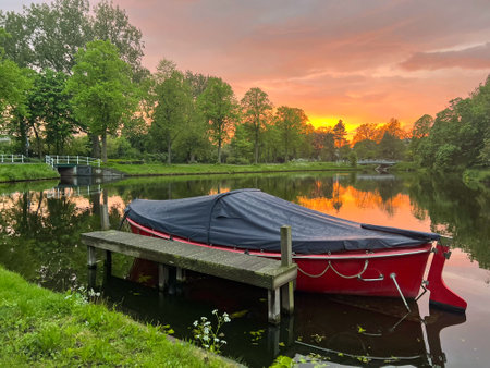 Scenic view of pond with moored boat at sunsetの写真素材