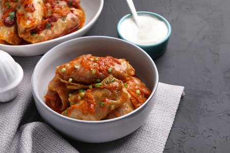 Delicious stuffed cabbage rolls cooked with homemade tomato sauce on black textured table, closeupの写真素材