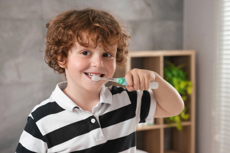 Cute little boy brushing his teeth with electric toothbrush in bathroomの写真素材