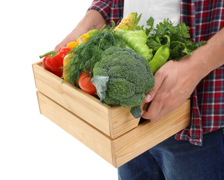 Harvesting season. Farmer holding wooden crate with vegetables on white background, closeupの写真素材