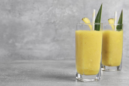 Tasty pineapple smoothie on light gray table, space for textの写真素材