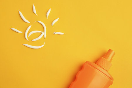 Drawing of sun and bottle with sunscreen on orange background, top view. Skin protection
