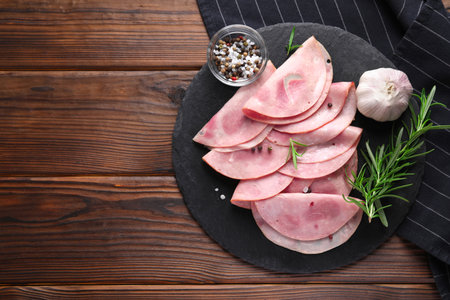 Tasty ham with rosemary, garlic, sea salt and peppercorns on wooden table, top view. Space for textの写真素材